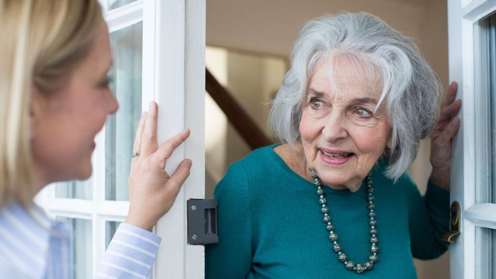 young woman talking to elderly woman in doorway