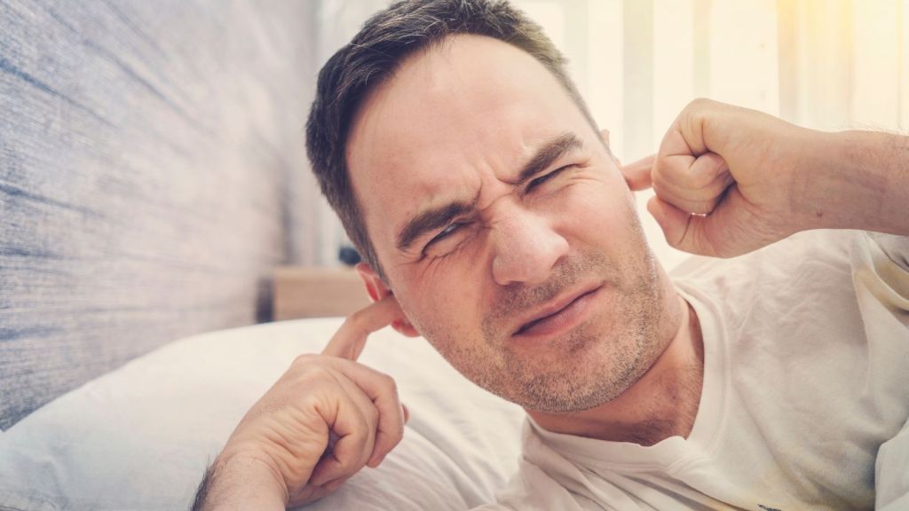 man plugging his ears with his fingers due to noise
