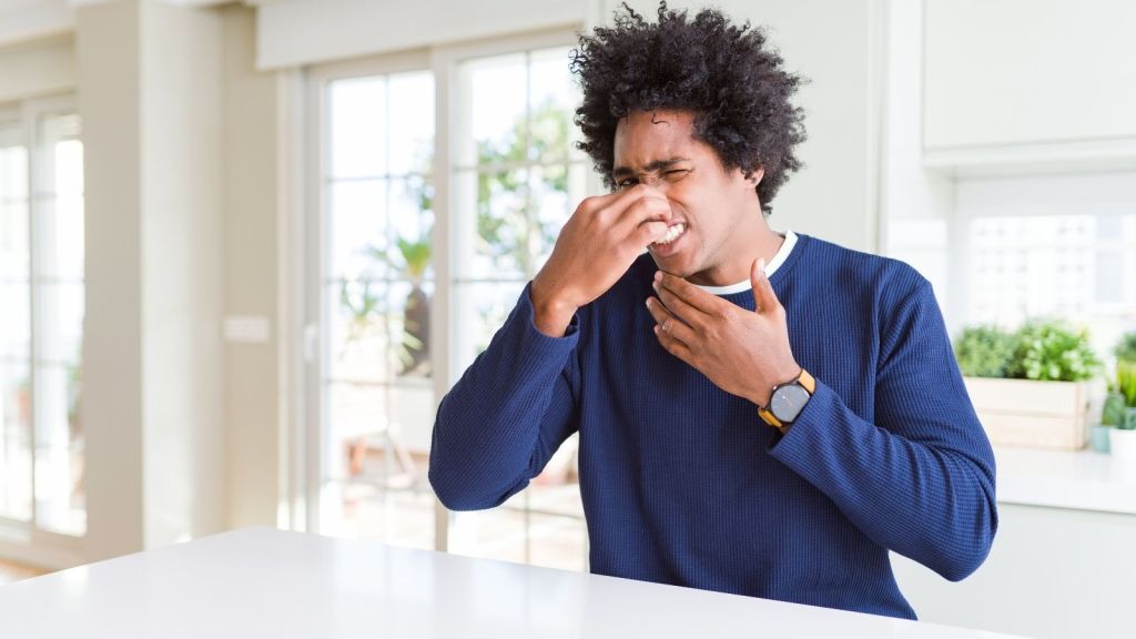 man plugging his nose because of a bad smell