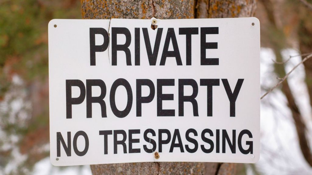 sign posted on a tree that reads "private property no trespassing"