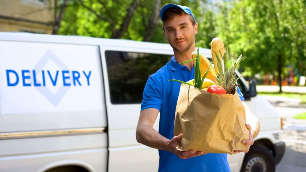 grocery store delivery driver holding a bag of food
