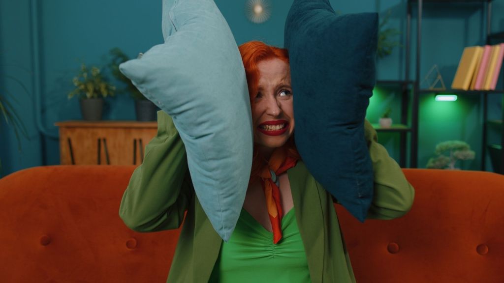woman holding pillows to her ears to block noise