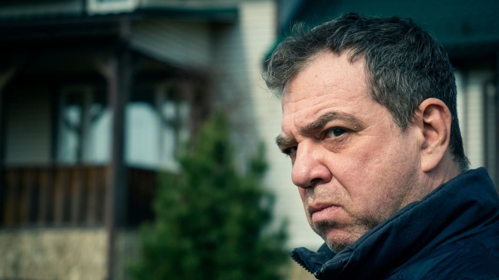 angry man standing outside house staring