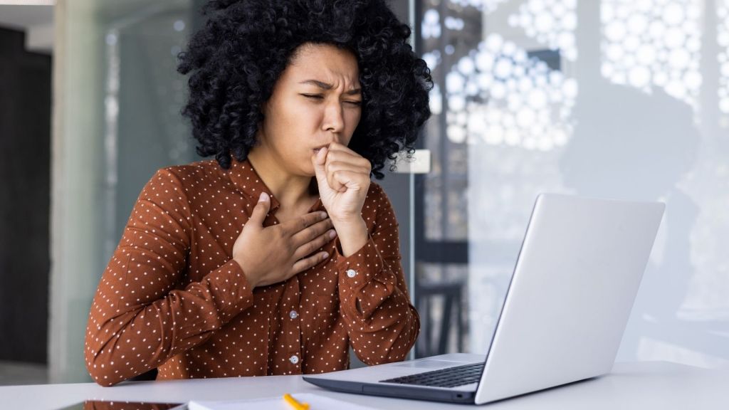 young woman coughing at work