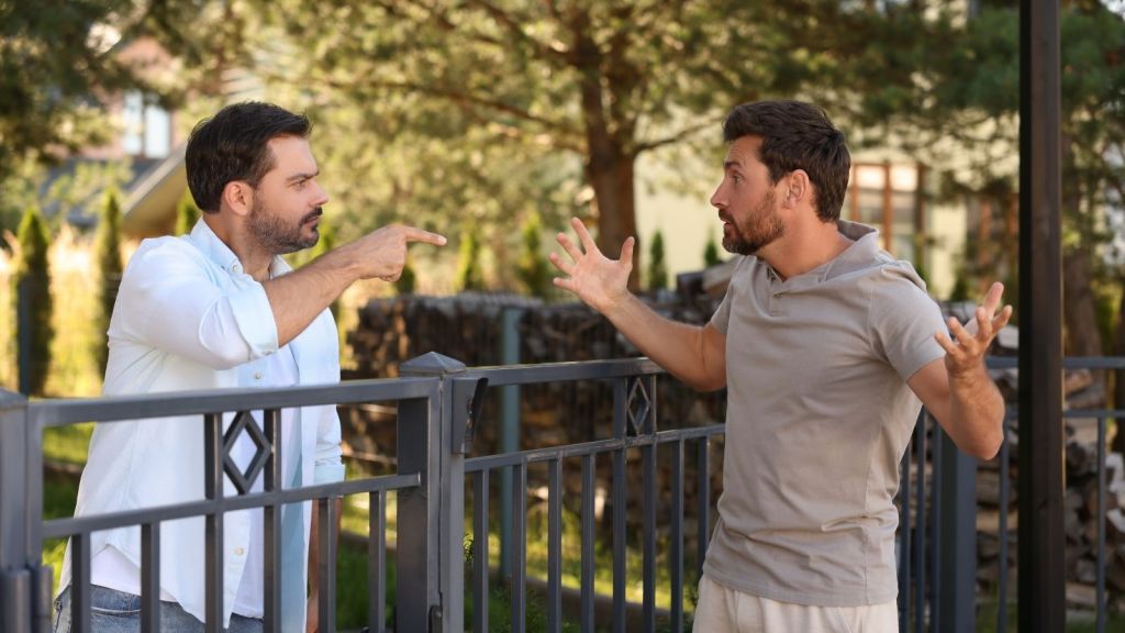 two men arguing across a fence