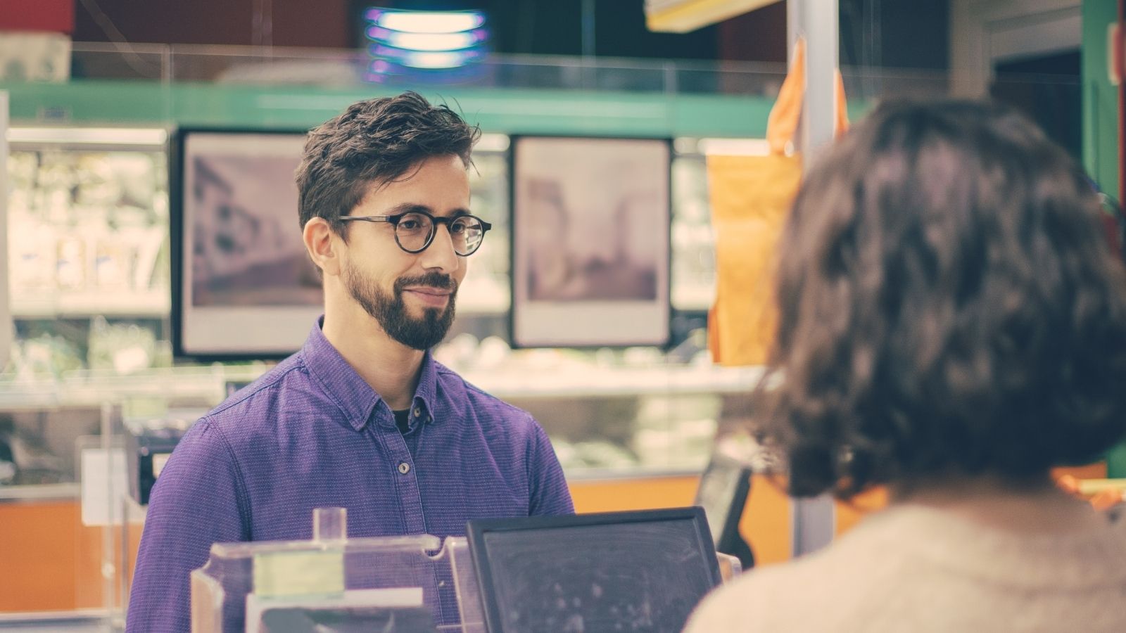 man and woman talking at cash register at store