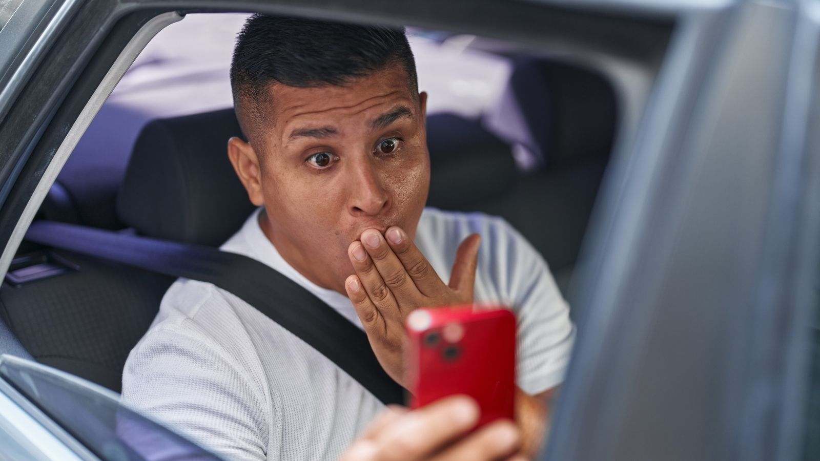 Neighbor Keeps Filming A Couple In The Parking Lot—But Police And Landlord Wont Help man sitting in car holding phone up looking surprised