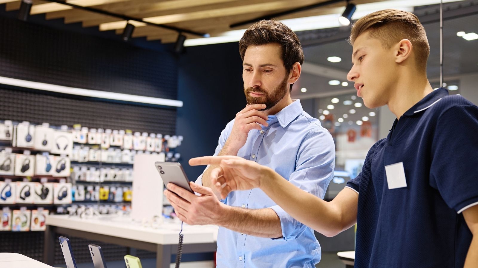 He Needed It More Than Anyone: Cashier Quietly Pays for Struggling Customers Phone Plan After Generous Act employee helping customer decide on a phone
