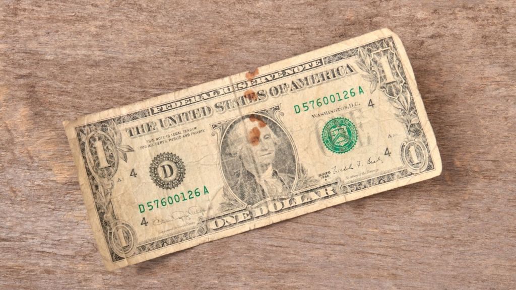 old one dollar bill on a wooden table