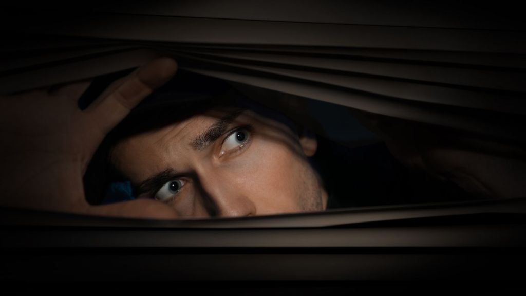 worried man looking out window at night