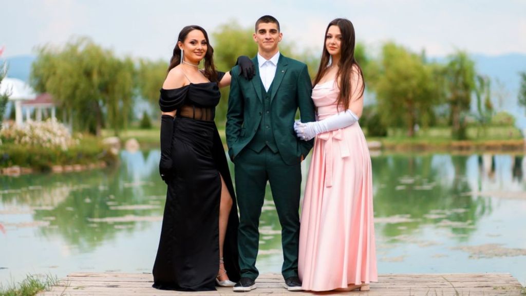 Young adults in nice outfits pose for a photo near the lake