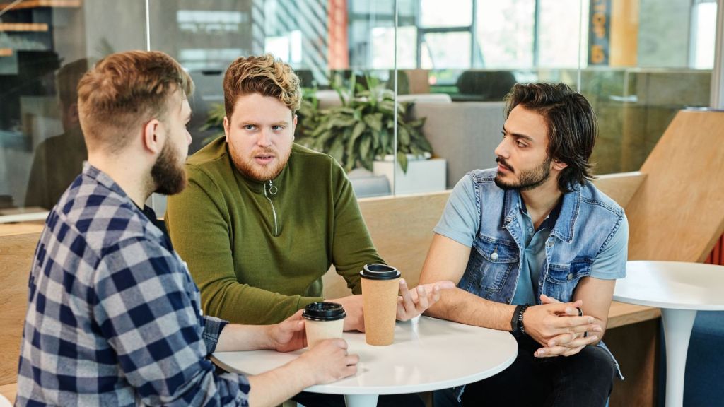 3 men talking in a cafe about some serious matter