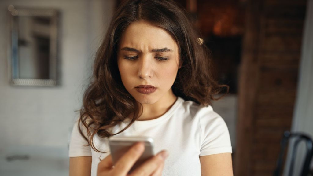 Woman feeling upset after reading a text message
