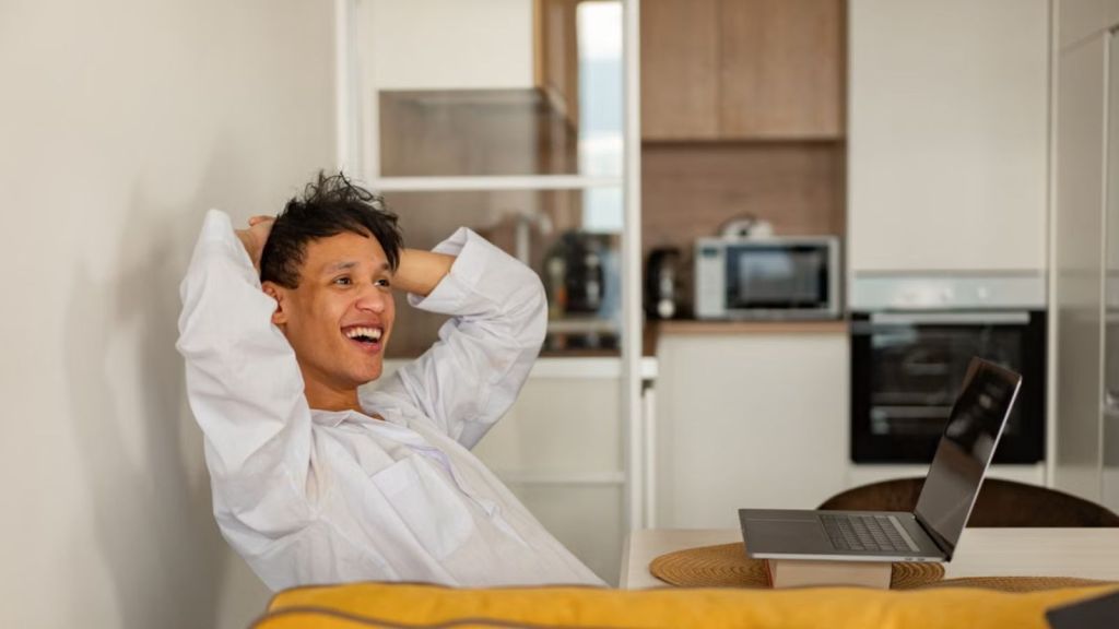 Man feeling happy and relaxing while working from home in front of a laptop