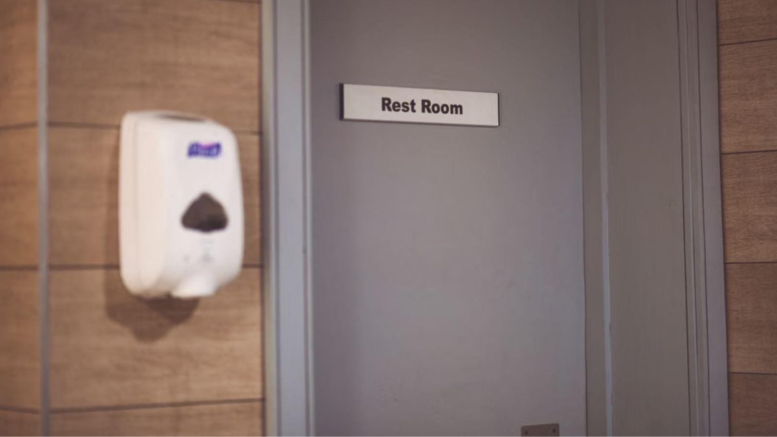 A restroom door with a label in front and a sanitizer dispenser on the side