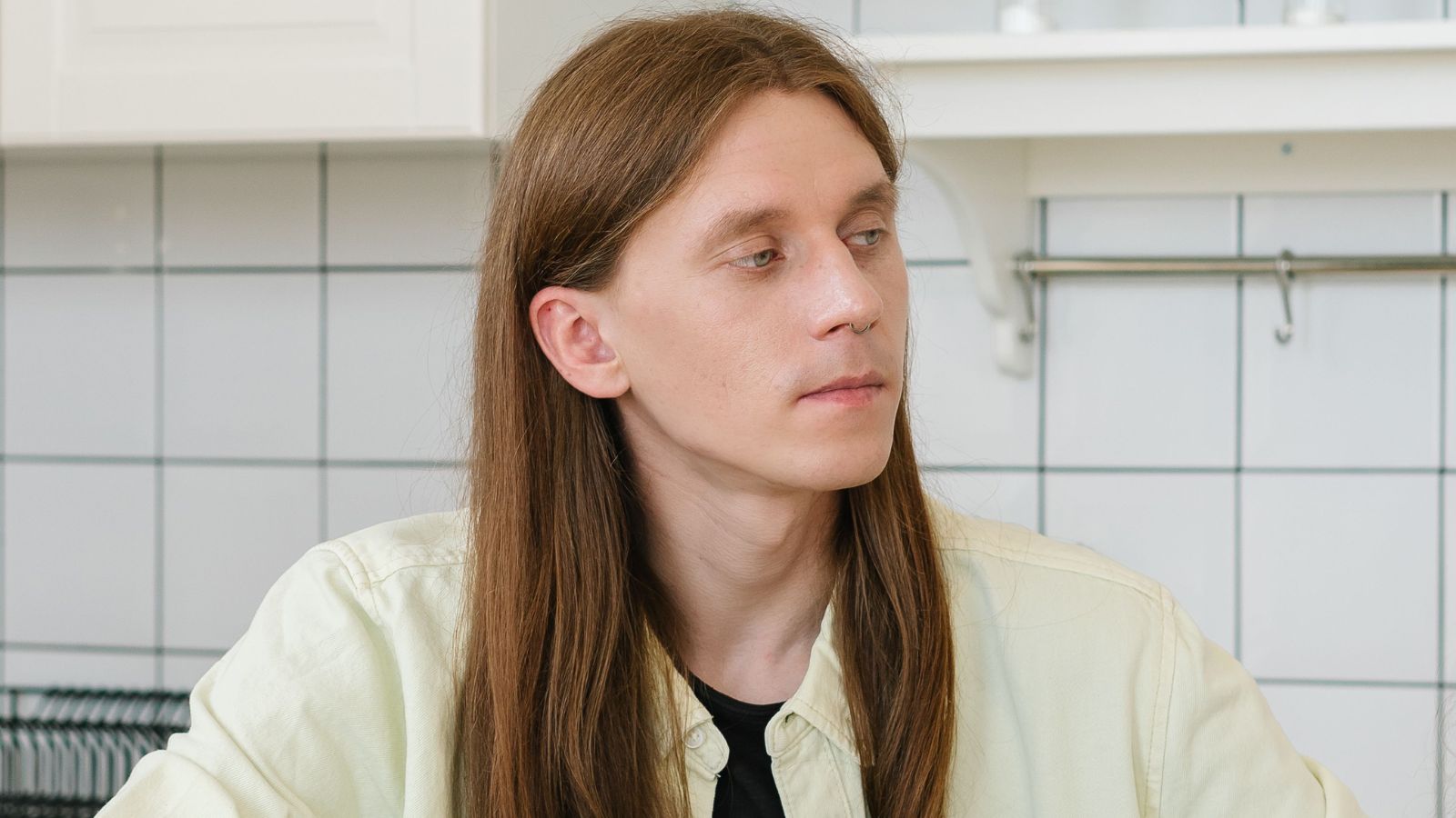 Man with long hair sitting in the kitchen