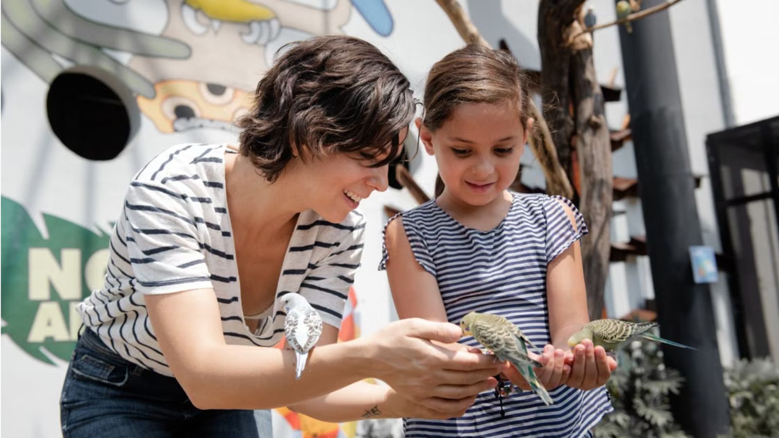 She Lost Her Father—Now She’s Questioning Whether Her Younger Sister Should Attend the Funeral at All Woman and little girl interact with colorful parrots in an outdoor setting