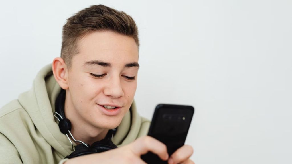 Teenage boy smiling while looking at his phone