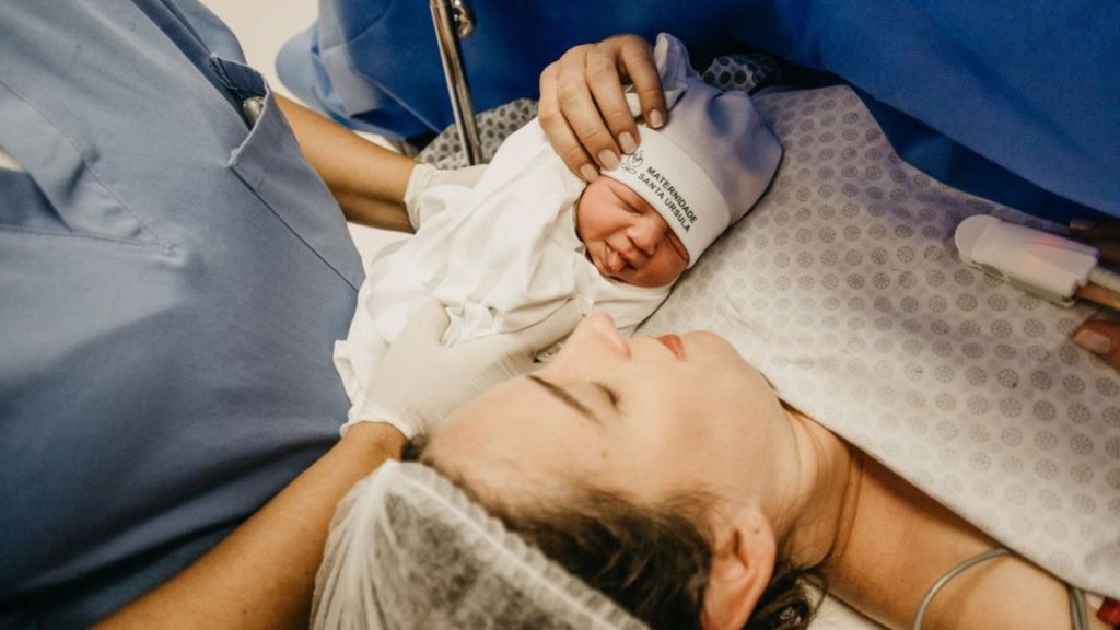 A mother cradling her newborn immediately after childbirth in the hospital