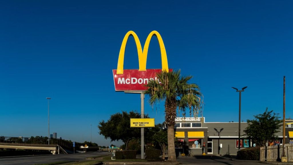 McDonald's golden arches sign with palm tree in front of a clear blue sky in Houston, TX