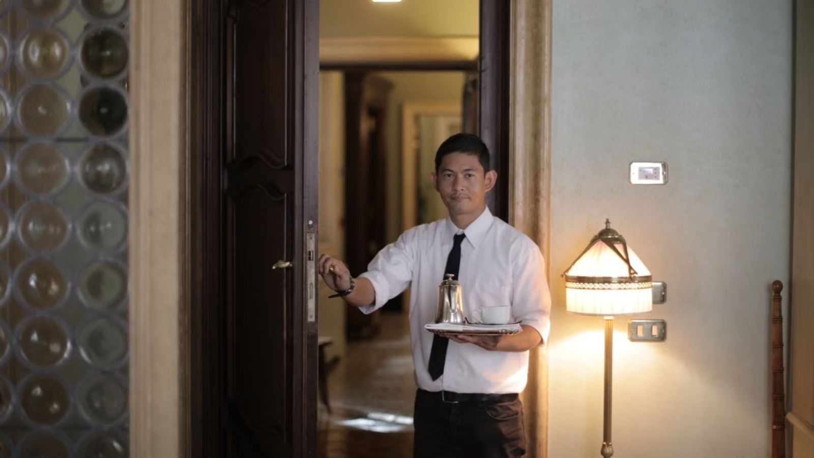 Hotel employee carrying a tray in an elegant hotel room