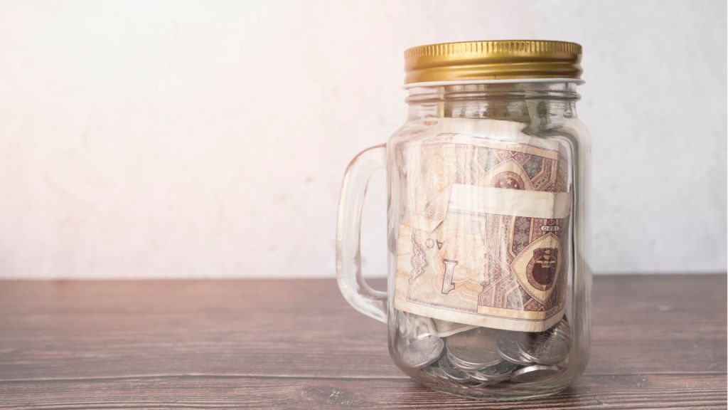 A closed jar with handle and money inside