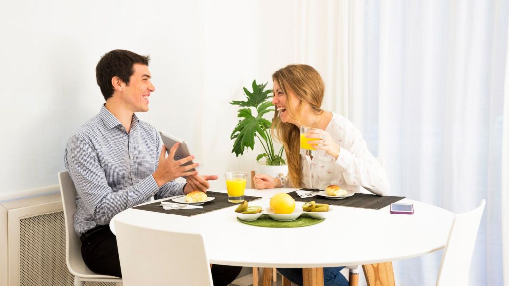 Woman laughing while having a meal with a man at home