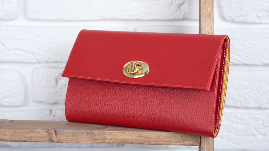 Red woman's leather clutch laying on a wooden shelf