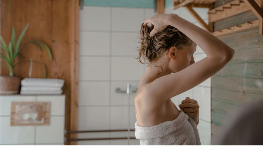 Woman holding her hair up after showering in the bathroom