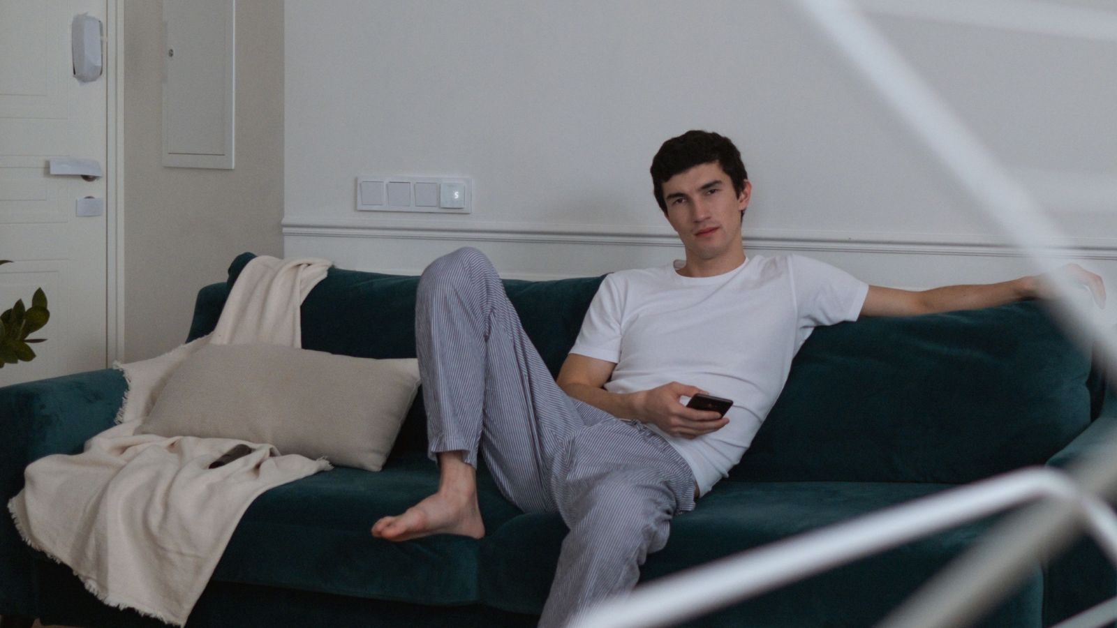 She Started Over In A New City—Then Her Roommates Boyfriend Became A Constant Problem Man casually sitting on a couch inside the apartment