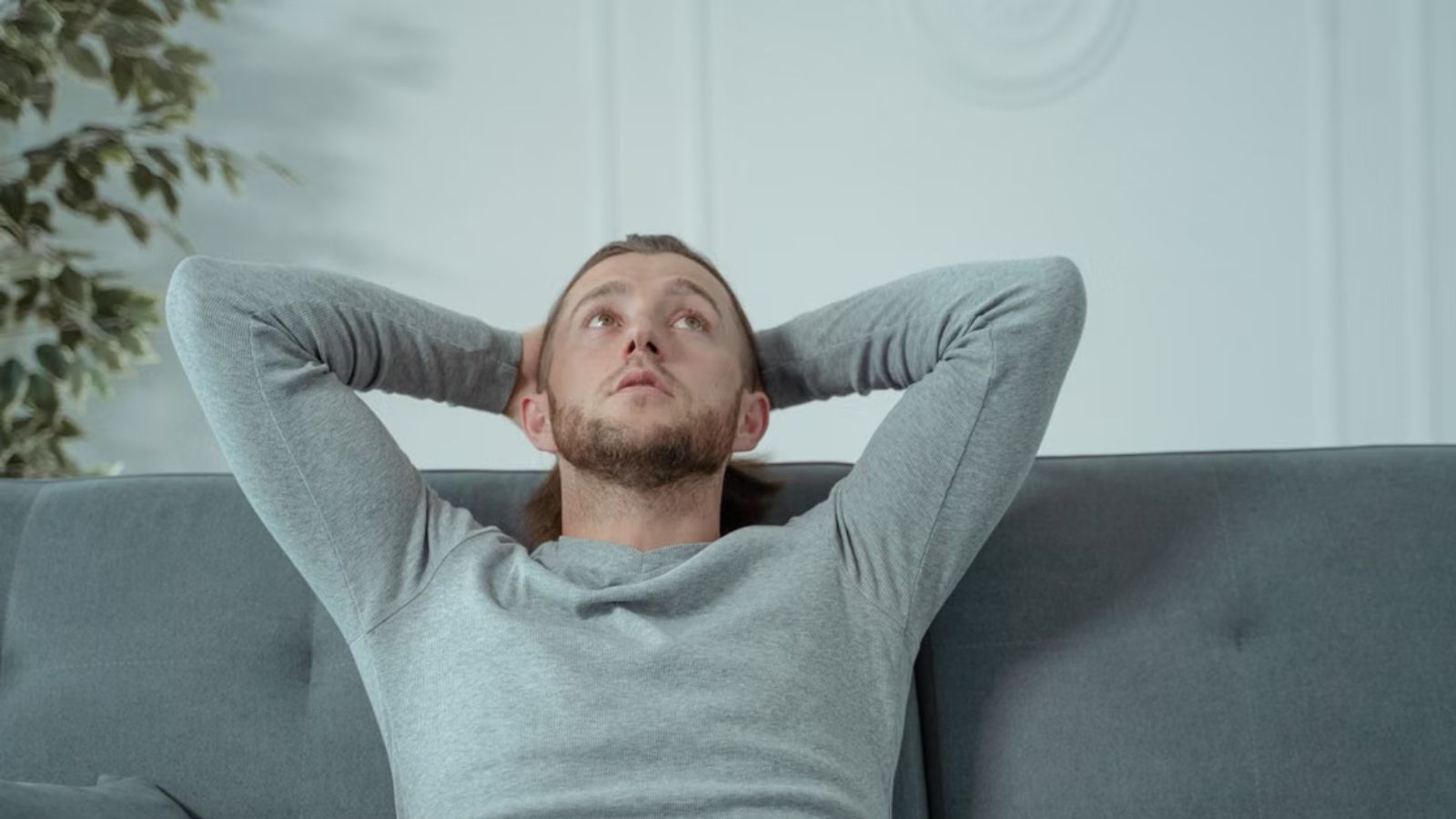 Man realxing on the couch with his hands at the back of his head