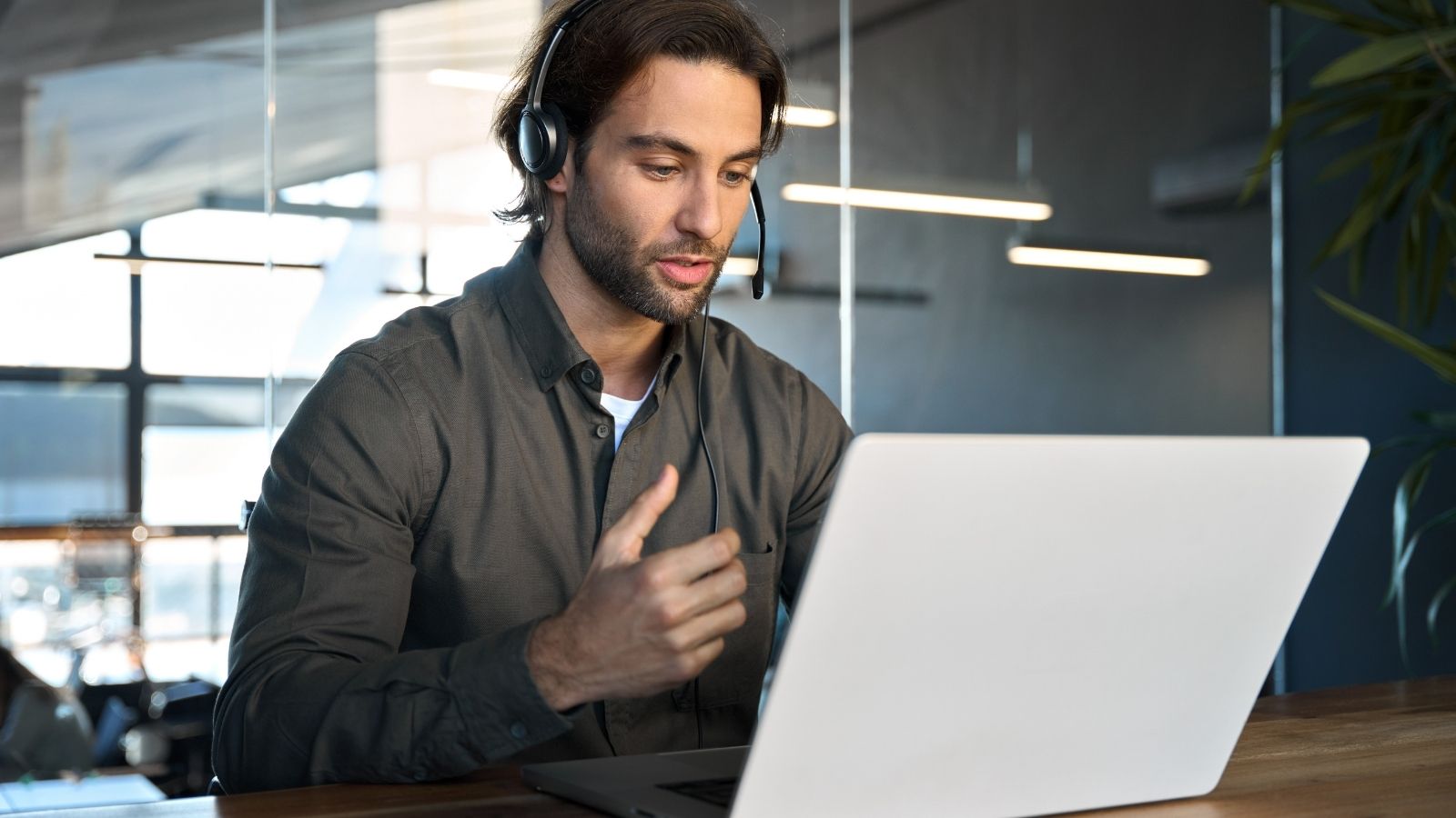 man wearing a headset and looking at a laptop