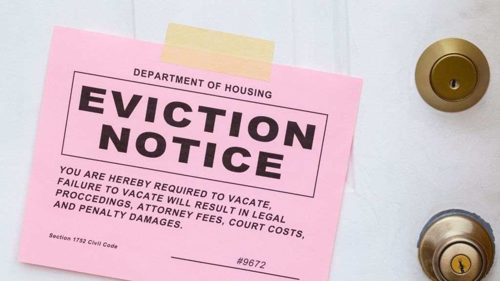 pink eviction notice taped to a white door