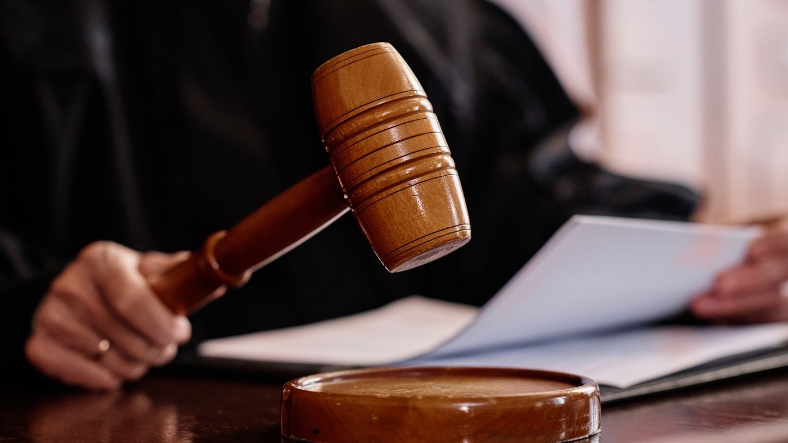 judge holding paperwork and a wooden gavel