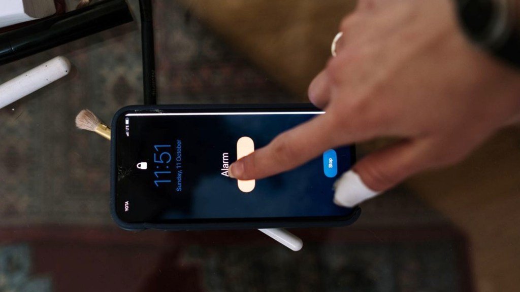 Person turning off alarm on iPhone