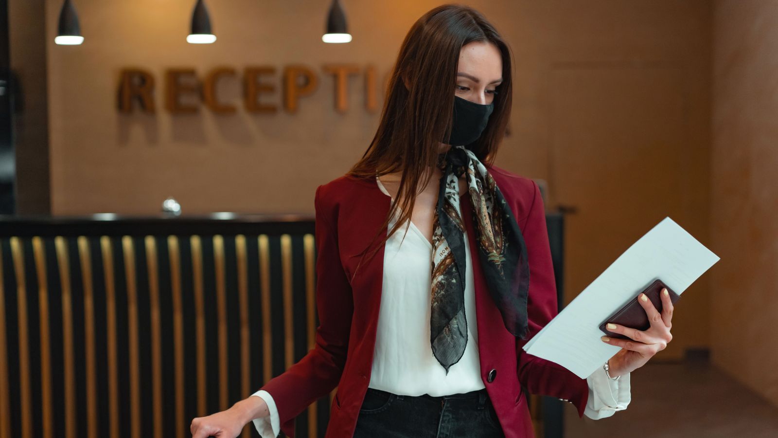 Front Desk Employee Faces Angry Guest After Explaining the Hotel Had No Vacancies receptionist in a mask looking at a sheet
