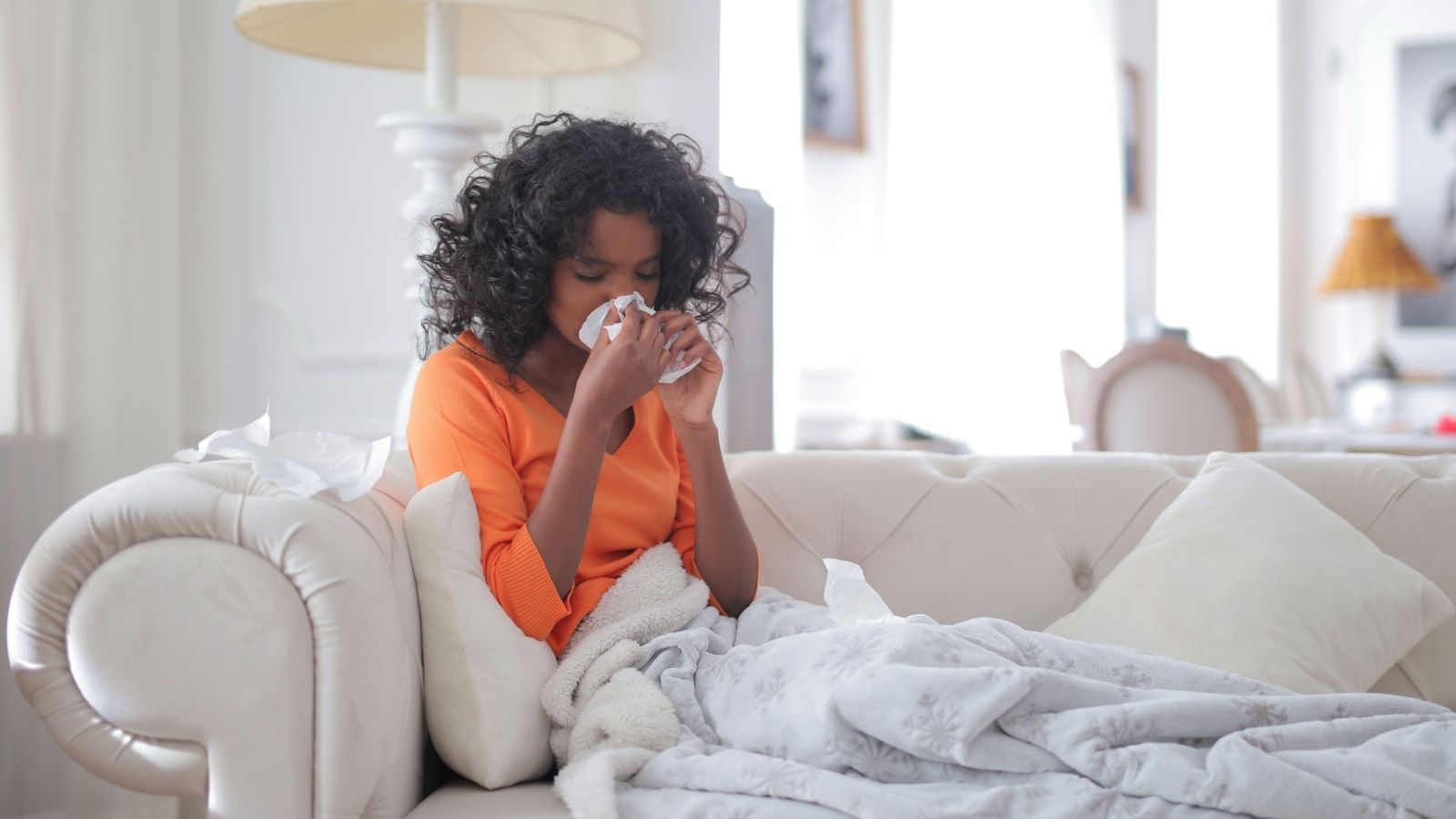 She Worked Through a Sick Holiday to Save Their Group Project Alone. Her Coworker’s Next Request Was Met With a Cold No. Woman on couch blowing her nose, on phone