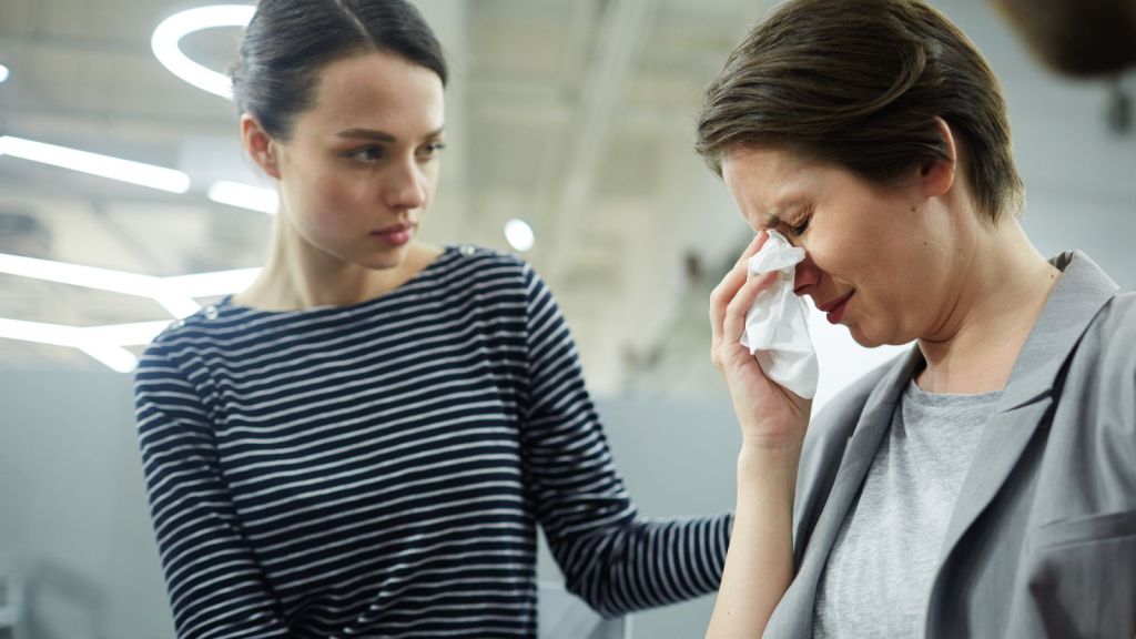 Woman crying while a friend supports her