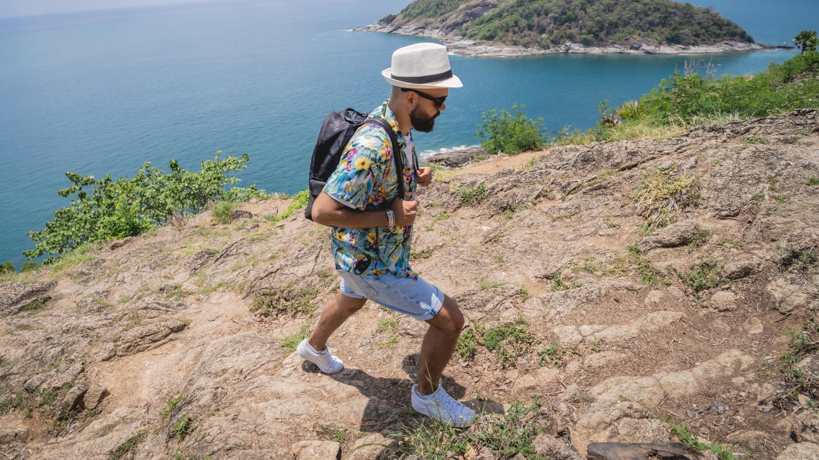 His Girlfriend Got Sick on Vacation. Now She Expects Him to Waste the Entire Trip in the Room With Her. man hiking on an island