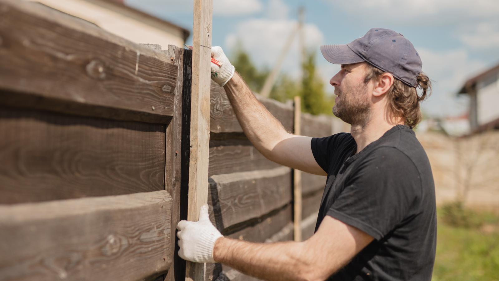 The Backyard Border War: Why One Family Is Reporting Their Neighbor’s Invasive Construction to Code Enforcement man building a fence