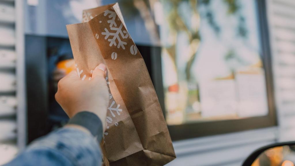 holding a brown bag in fast food drive through