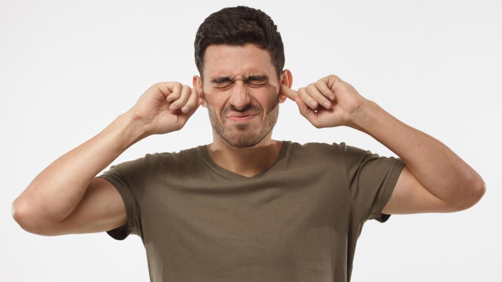 man plugging his ears