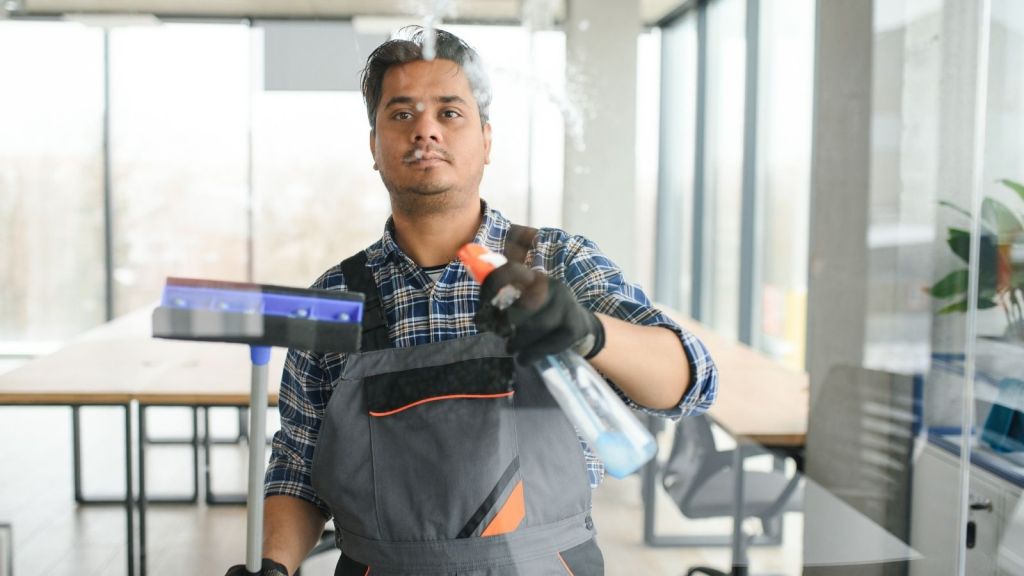 male janitor cleaning a window