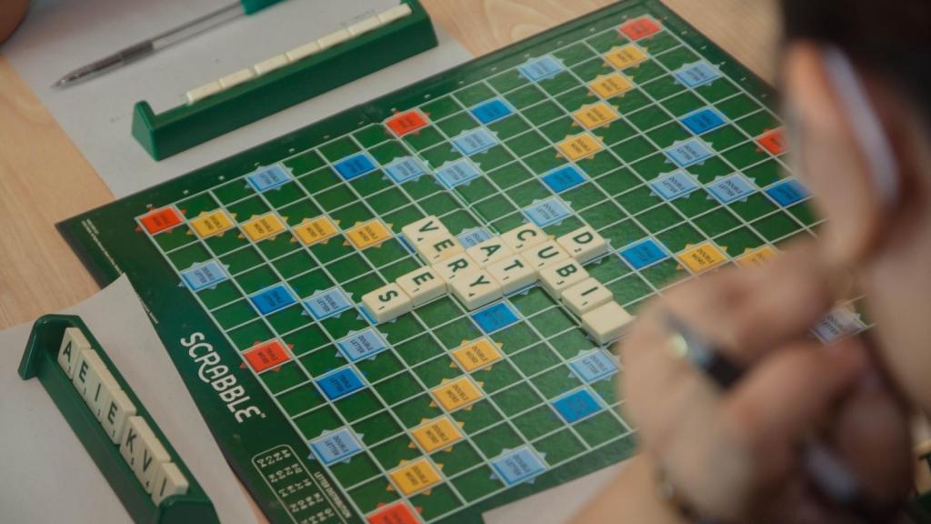 man looking at a green scrabble board