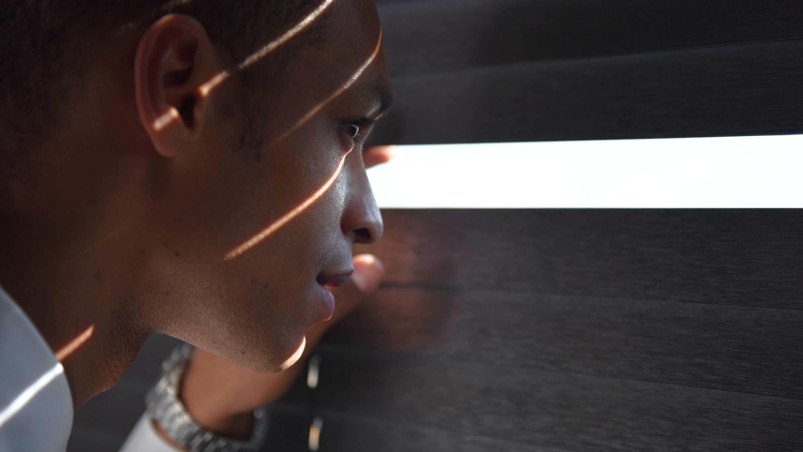 man looking through window shade