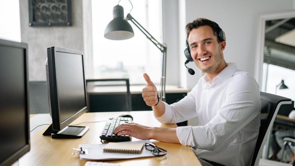 man smiling at his desk giving thumbs up