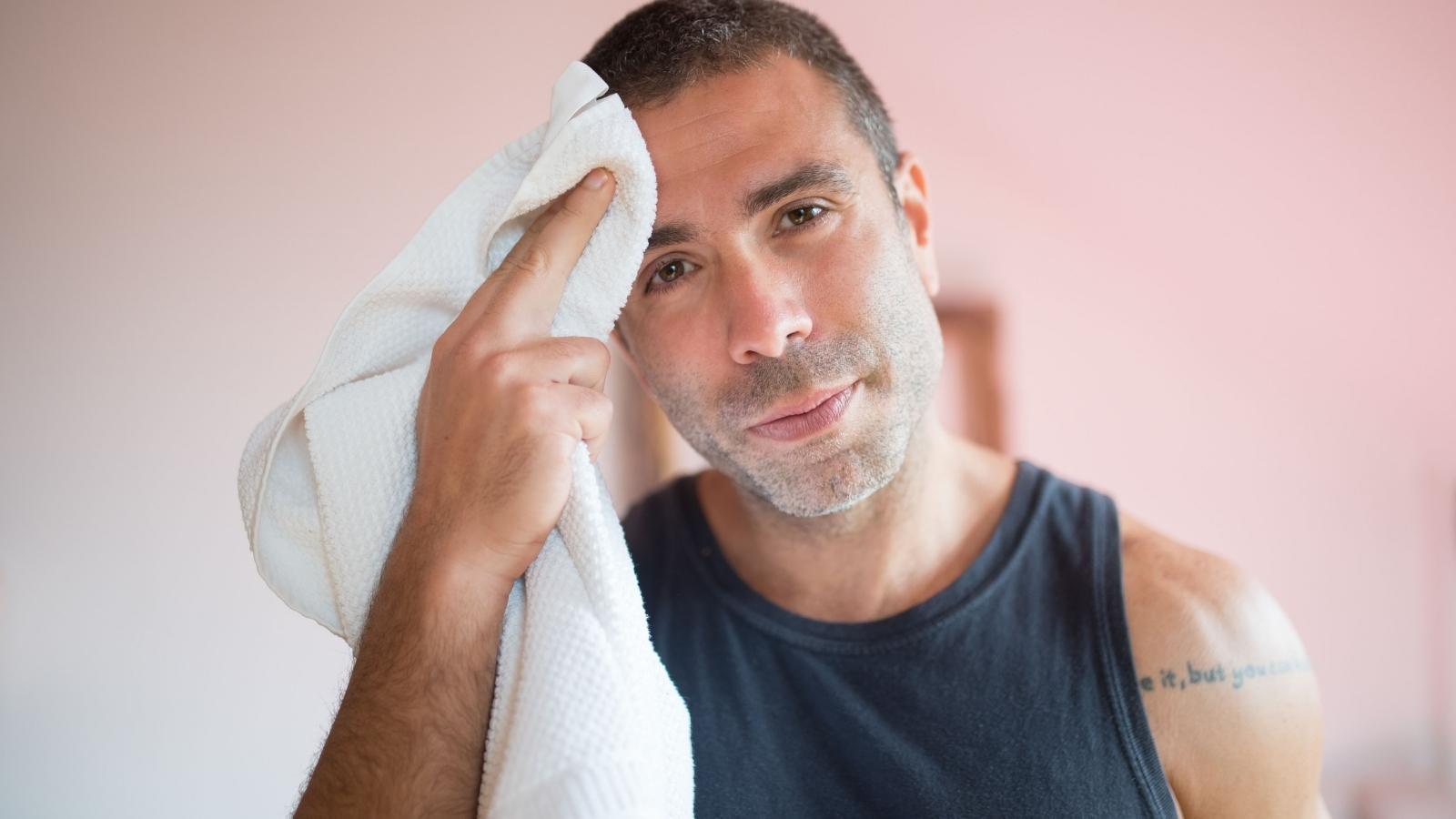 man wiping off sweat with towel