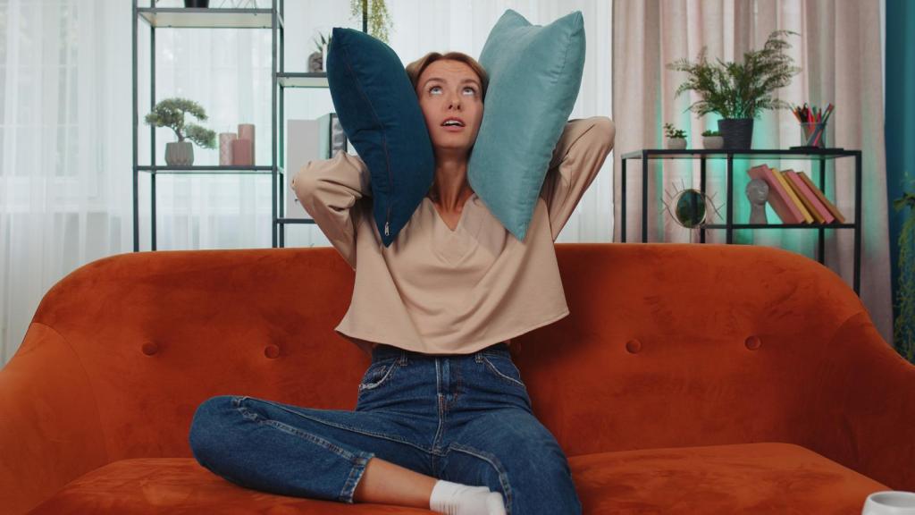 woman holding pillows to her ears