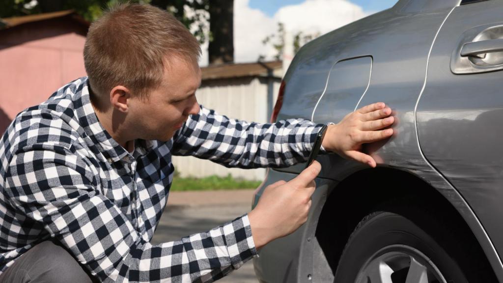 man looking at his car