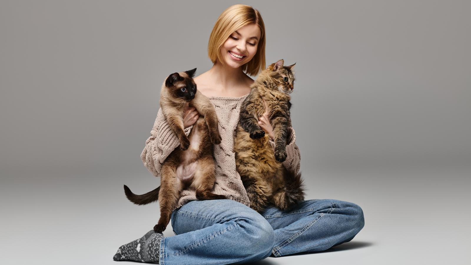 Her Roommates Want Her to Get Rid of Her Cats — Shes Refusing, And Now Its a Standoff woman holding two cats
